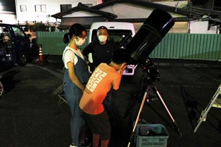 大きな望遠鏡をのぞき込む参加者