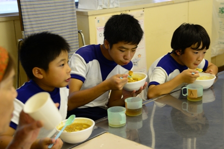 アルファ米で作った夕食を食べる児童たち