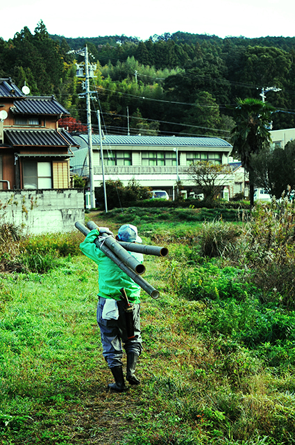 太い竹を肩に担いで運ぶ人