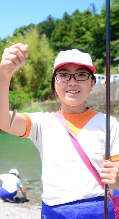 釣り上げた魚を掲げる女子児童